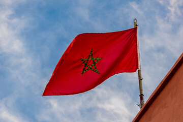 Morocco flag with green star waving in the wind against a blue sky in Marrakesh, symbolizing national pride, heritage, tradition, freedom and the vibrant cultural identity of the North African country