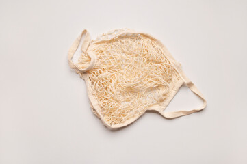 Eco-friendly string bag, shopping mesh bag of cotton threads on light gray background top view. Zero waste and plastic-free concept. Bag for buying fruits, vegetables and groceries