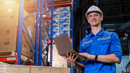 A warehouse worker using a laptop in a storage warehouse.