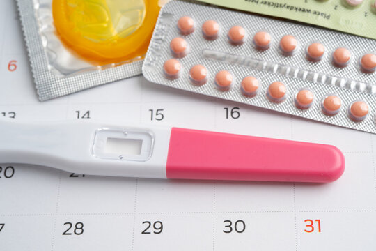 Pregnancy test and birth control pills on calendar, contraception health and medicine.