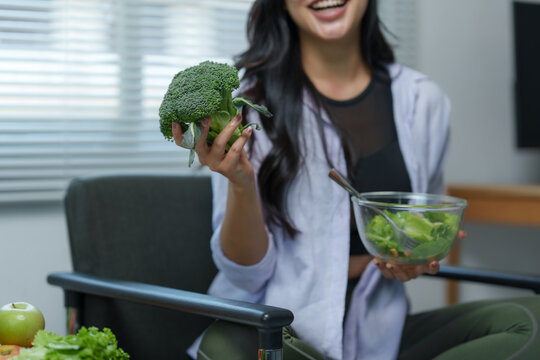 Smiling young woman enjoying a healthy meal of fresh salad and broccoli, promoting a balanced diet and active lifestyle for overall well being