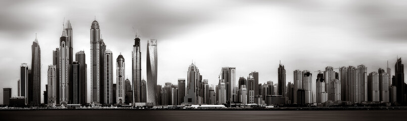 Obraz premium Monochrome city skyline with tall skyscrapers reflecting on calm water under a cloudy sky, Dubai Marina bay UAE