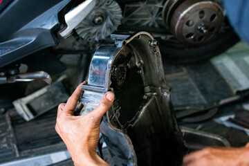 Mechanic cleaning a CVT motorcycle cover using a special liquid and a brush during maintenance