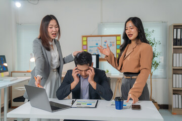 Two businesswomen blaming their stressed male colleague at the office, pointing to mistakes in the...