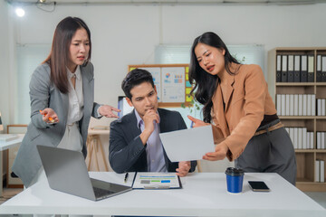 Two young businesswomen showing disagreement and concern to a pensive businessman about a project...