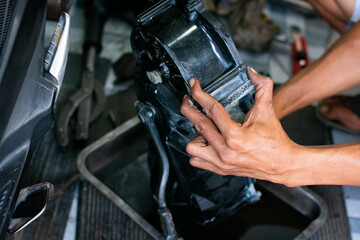 Close-up of a mechanic’s hands cleaning a scooter’s CVT housing using a special cleaning liquid during routine maintenance