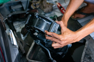 Close-up of a mechanic’s hands cleaning a scooter’s CVT housing using a special cleaning liquid during routine maintenance.