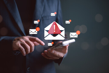 Businessman checking smartphone with warning email icons. Concept of spam alert, phishing scam, email security threat, cyber attack risk, and digital communication protection.