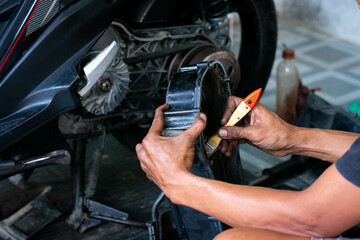 Mechanic cleaning a CVT motorcycle cover using a special liquid and a brush during maintenance