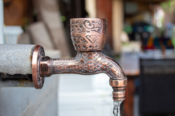 A flowing water stream from a copper tap with beautiful engravings, symbolizing clean water access...