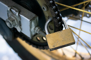 close up view of a padlock installed on a motorcycle chain as an additional anti-theft security system