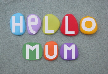 Hello Mum, creative and lovely message composed with multi colored hand painted stone letters over green sand
