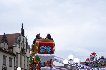 A back view of people enjoying a Christmas sleigh ride attraction against the backdrop of historic buildings in Wroclaw, Poland