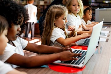 Diverse students, girls and boys, learn on laptops in classroom. Diverse students focused on their laptops, learning together. Diverse student learning through laptop. Boys and girls learning, laptop