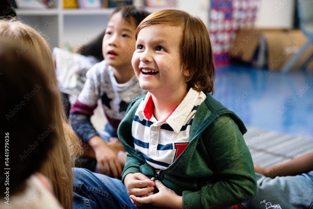 Poster happy caucasian boy smiling and sitting with other children in classroom. boy in classroom with othe