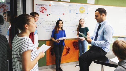 Group of students and a teacher in a classroom discussing. Diverse student group learning in class....