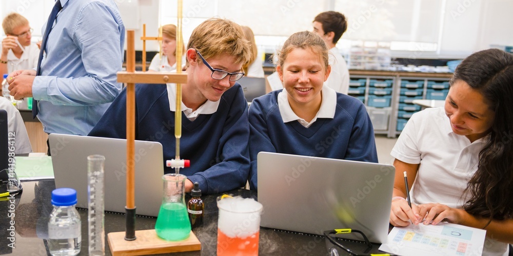 Poster students in a science lab working on laptops. chemistry equipment on the table. engaged students, co