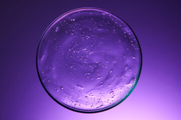 Top view of clear thick liquid with molecular bubbles stuck together. Petri dishes with cosmetic...