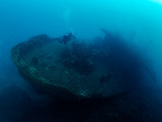 unrecognizable scuba diver diving on a sunken ship in the blue ocean, concept of underwater...