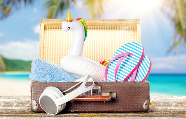 A bag with beach towels, sunglasses, and flip flops placed on a table