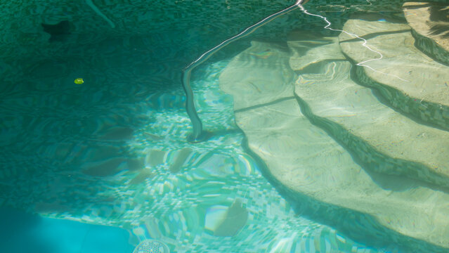 crystal clear blue turqoise swimming pool water background with steps and railing stairs