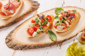 Tasty antipasto toasts featuring classic caprese with mozzarella and tomatoes, and savory prosciutto with herbs