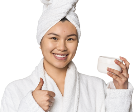 Chinese woman with moisturizer in robe smiling and raising thumb up