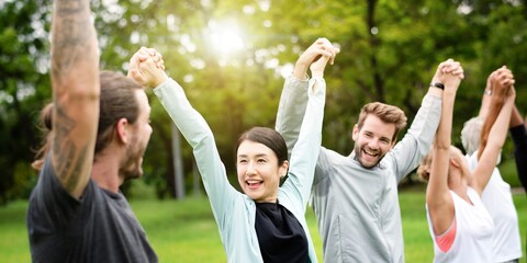 Unity, teamwork, success. Group of diverse men and women, hold hands in a park. Happy men and women...