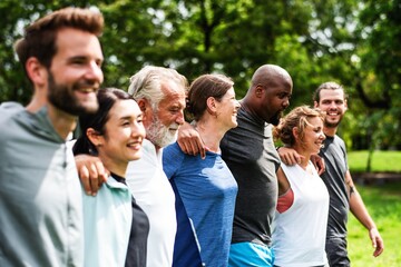 Diverse group of people outdoors, smiling and embracing. Multiracial, mixed gender group enjoying nature. Happy, diverse friends in a park setting. Diverse people group in park outdoor.