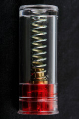 dummy cartridge, blank firing cartridge design close up, spring and internal parts, black background, macro