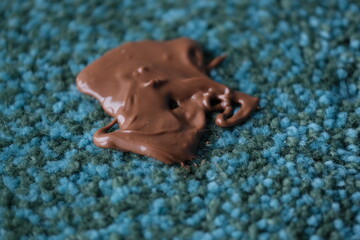 Spilled chocolate on a textured blue carpet in the living room. Daily stains concept on different surfaces