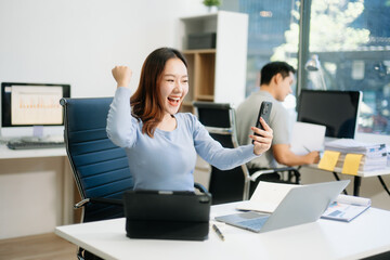 Asian business woman are delighted and happy with the work they do on their tablet, laptop and taking notes