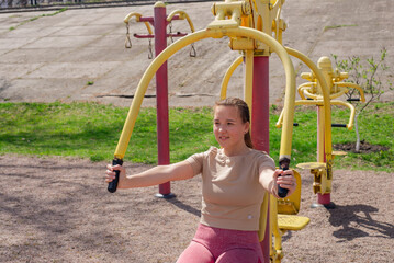 Girl exercising on outdoor exercise equipment in the park