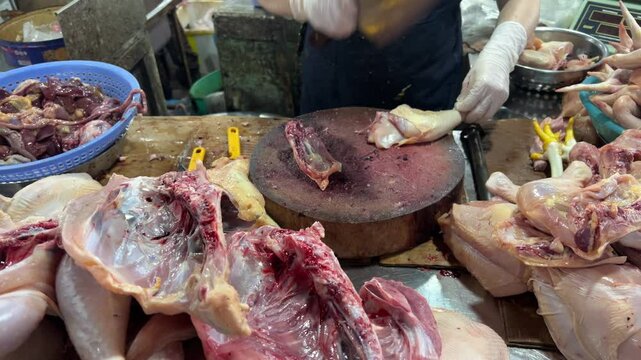 Tondano, Indonesia - April, 10 2025 : A chicken vendor is cutting raw chicken meat. The scene shows a typical meat preparation process at a local market separate the chicken parts for sale
