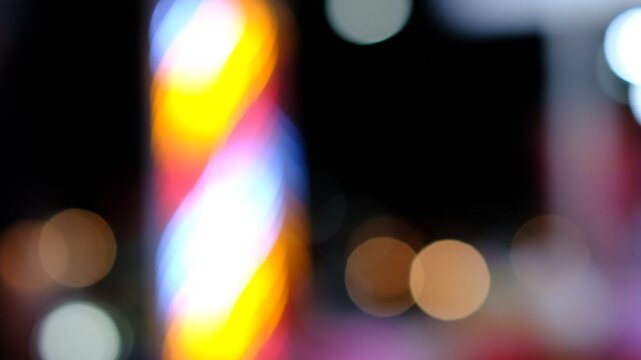 A blurry image of a barber pole with a neon sign on top