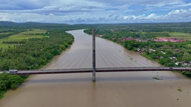 A high aerial pan left to right above the Macapagal Bridge bypassing Butuan City across the Agusan River in Mindanao, Philippines, showcasing this vital transportation link.