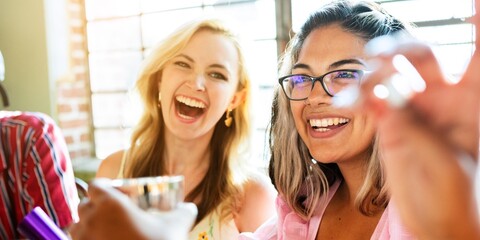 Group of friends laughing and enjoying drinks together. Happy diverse women having fun with friends. Smiling faces, joyful moments, and friendship in a lively cheerful restaurant
