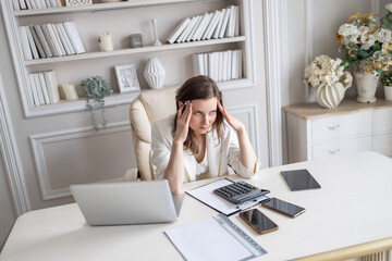 A business lady is sitting at a desk in a bright office. The plot of a tense situation, problems...