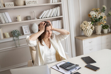 A business lady is sitting at a desk in a bright office. The plot of a tense situation, problems...