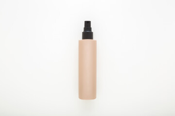 Beige plastic spray bottle for hair on light gray table background. Female beauty product. Closeup. Top down view.