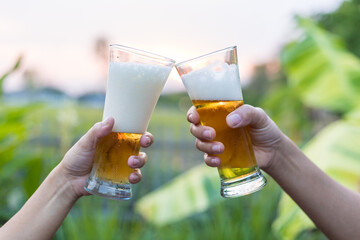 Close-up of hands holding a cold beer glass, condensation forming on the surface, capturing a moment of relaxation, enjoyment