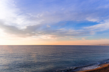 scenic sunrise or sunset above sea water with beautiful ocean vawes , nice golden evening clouds above horizon and awesome blue sky