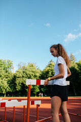 Teenage girl training at the stadium, doing track and field exercises, running and performing various athletic drills.