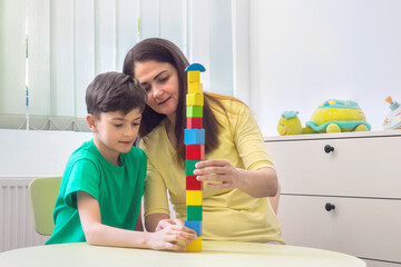 Child and Therapist Building Block Tower During Developmental Session. Autism spectrum disorder therapy techniques. psychological support for children.  Dyspraxia intervention activities. Inclusive 