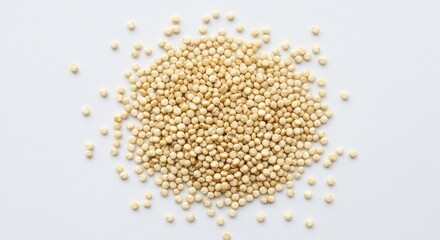 A top down view of a pile of quinoa seeds on a plain white surface, showcasing their texture and color