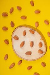 Stylish props and almonds seed on yellow background