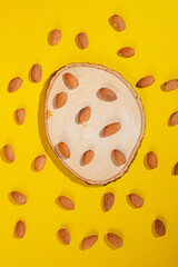 Stylish props and almonds seed on yellow background