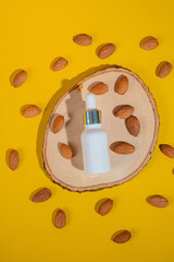 Cosmetic bottle, Skin care or sunscreen cosmetic with stylish props and almonds seed on yellow background