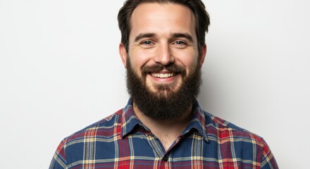Obraz premium Portrait of a smiling man with a beard wearing a plaid shirt against a white background studio shot