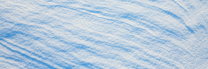 Obraz premium Beautiful winter background with snowy ground. Natural snow texture. Wind sculpted patterns on snow surface. Wide panoramic texture for background and design.